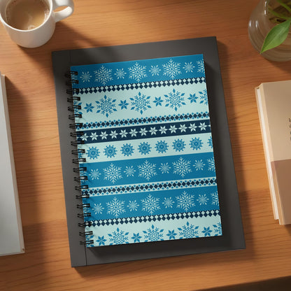 Notebook with blue and white snowflake pattern on wooden desk.