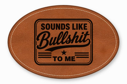 Brown oval leather patch with white stitched border and stamped black text that reads "Sounds Like Bullshit to Me."