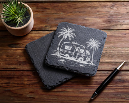 Slate coasters with etched camper van and palm tree design on a wooden table.