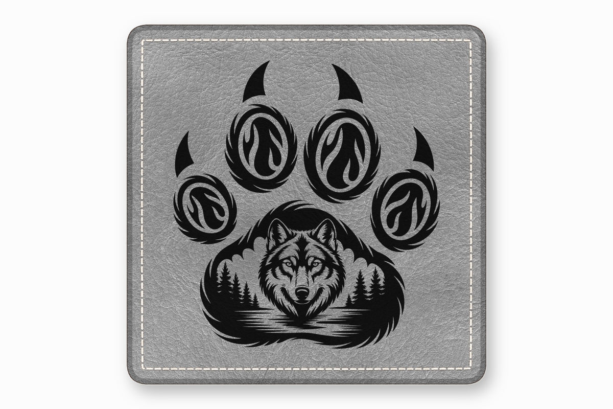 Gray square leather coaster featuring a black engraved paw print containing a wolf and forest design.