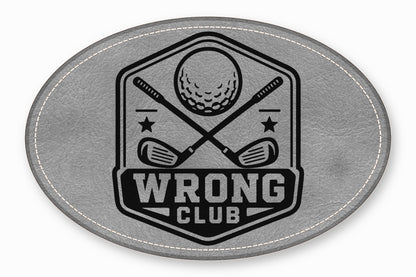 An oval grey leather patch with white stitching featuring a black golf emblem and the text WRONG CLUB.