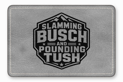 Grey leatherette rectangular patch with white stitched border and a black hexagon emblem reading Slamming Busch and Pounding Tush.
