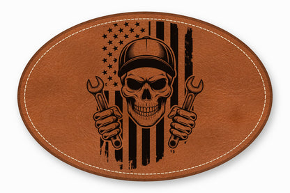 An oval brown leather patch featuring an American flag and mechanic skull graphic with wrenches.
