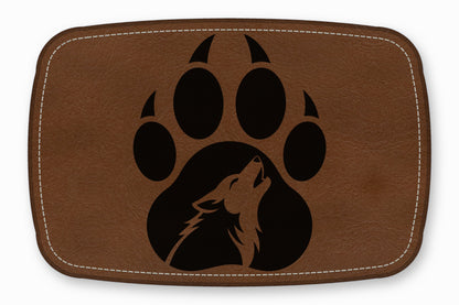 Brown leather patch with white stitching featuring a black bear paw print containing a howling wolf silhouette.