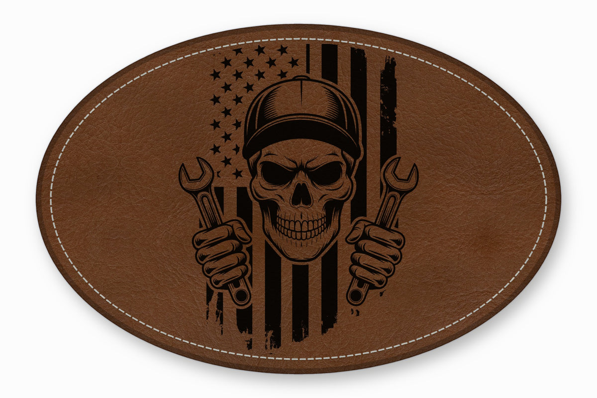 An oval brown leather patch features a black engraved skull holding two wrenches against a distressed American flag.