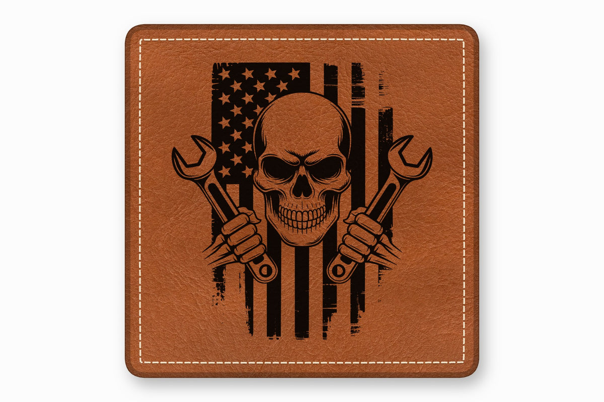 Brown square leather patch with white border stitching and a black distressed American flag, skull, and wrenches design.