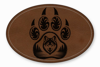 An oval brown leather patch with white stitching featuring a black bear paw and wolf graphic.