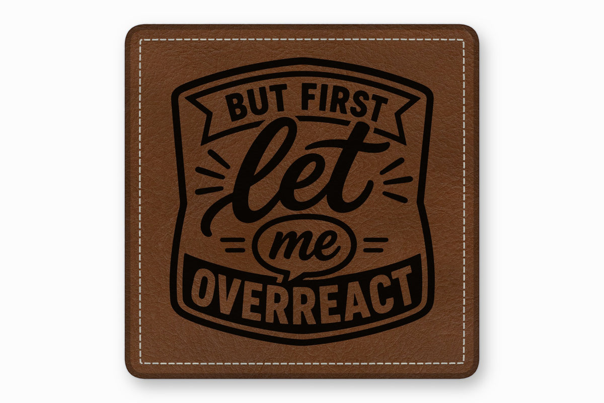 A square brown leather patch with white stitched borders and black text reading BUT FIRST let me OVERREACT.