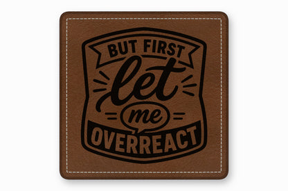 A square brown leather patch with white stitched borders and black text reading BUT FIRST let me OVERREACT.