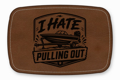 Brown leather patch with white stitched border, featuring a boat on a trailer and the text I HATE PULLING OUT.