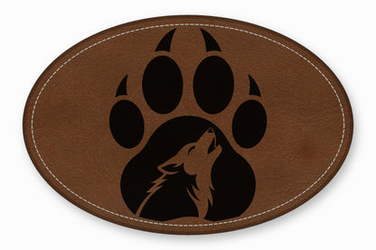 Brown oval leather patch featuring a black paw print with a howling wolf silhouette inside.
