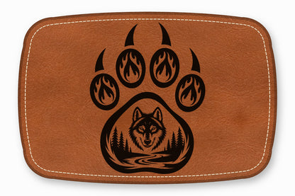 Brown leather patch featuring a black graphic of a bear paw with a wolf head, forest, and river.
