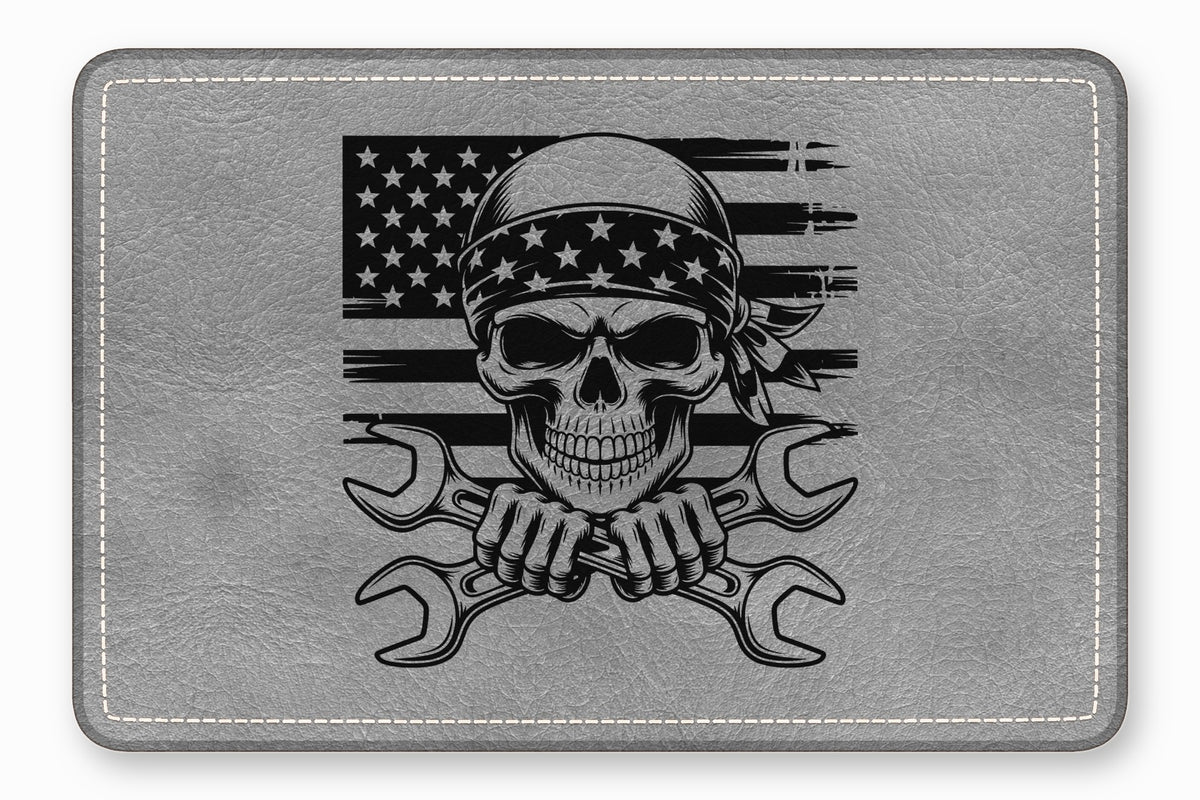 Grey leather rectangular patch with a black graphic of a skull wearing a star bandana and crossed wrenches against a distressed American flag.