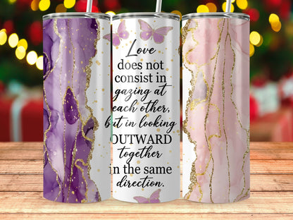 Tumblers with marble-like purple and pink designs, gold accents, and the quote "Love does not consist in gazing at each other, but in looking outward together in the same direction."