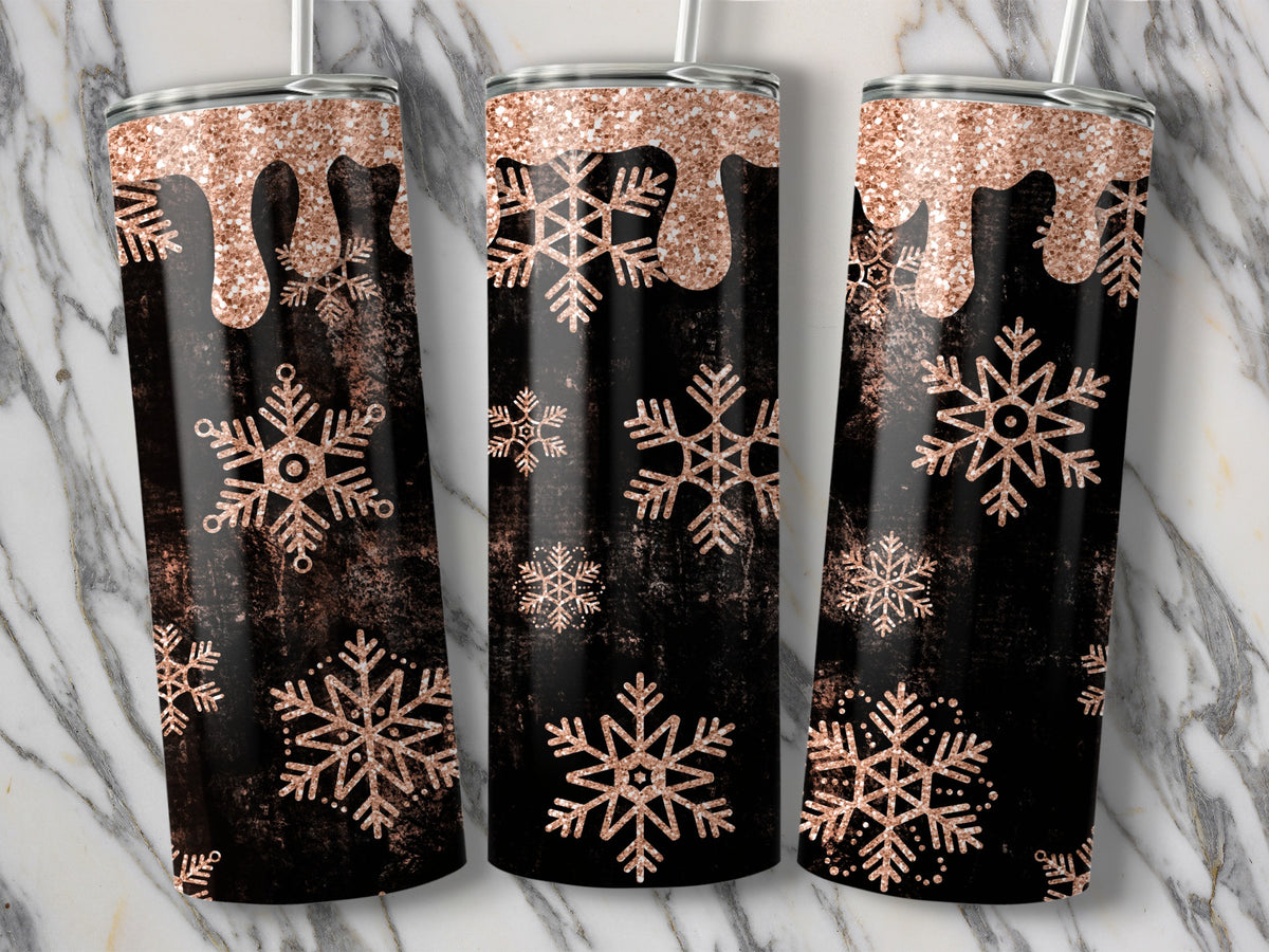 Three tumblers with a rose gold glitter drip and snowflake design on a black textured background.