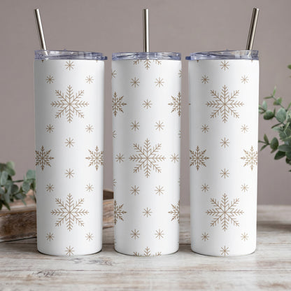 Three white tumblers with gold snowflake pattern and metal straws.