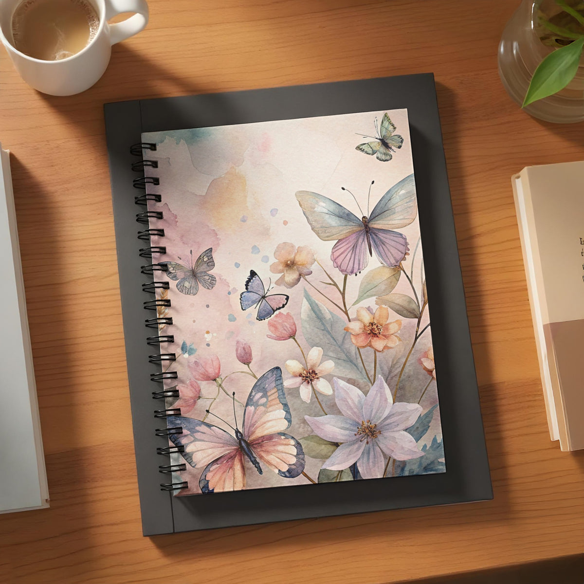 Spiral notebook with watercolor butterflies and flowers on a wooden desk.