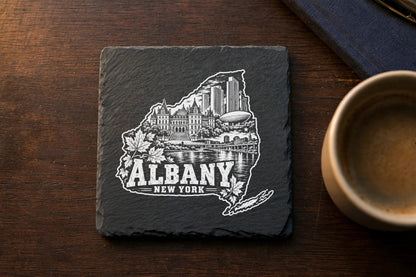 Square dark slate coaster laser-engraved with a white graphic of the Albany, New York skyline.