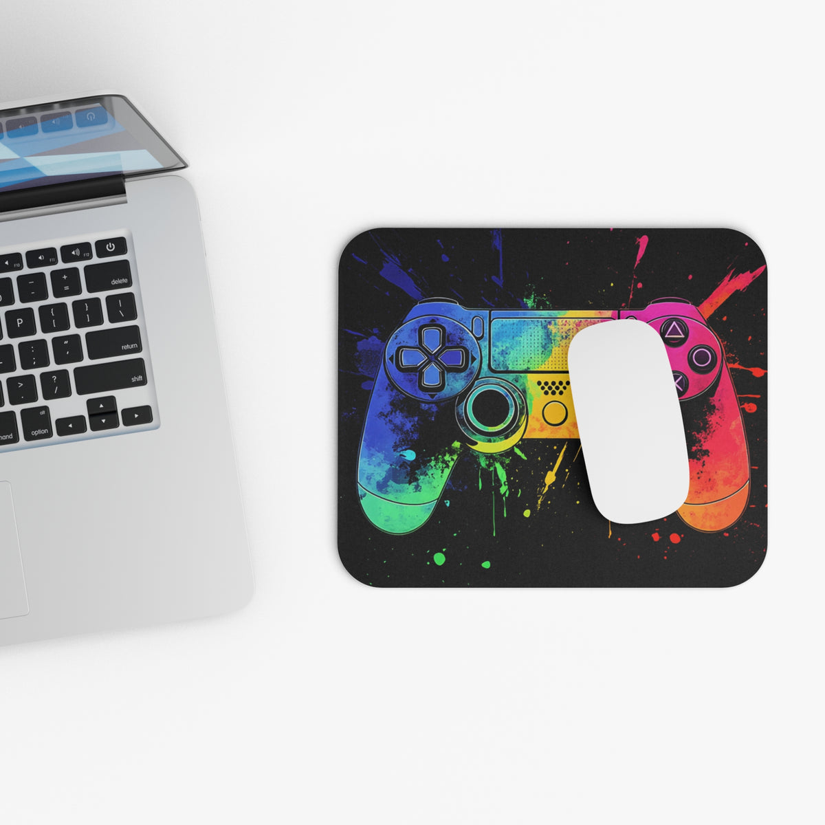 Colorful gaming controller design on a black mousepad next to a laptop.