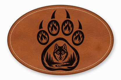 Oval brown leather patch with white stitched border featuring a black bear paw and wolf silhouette.