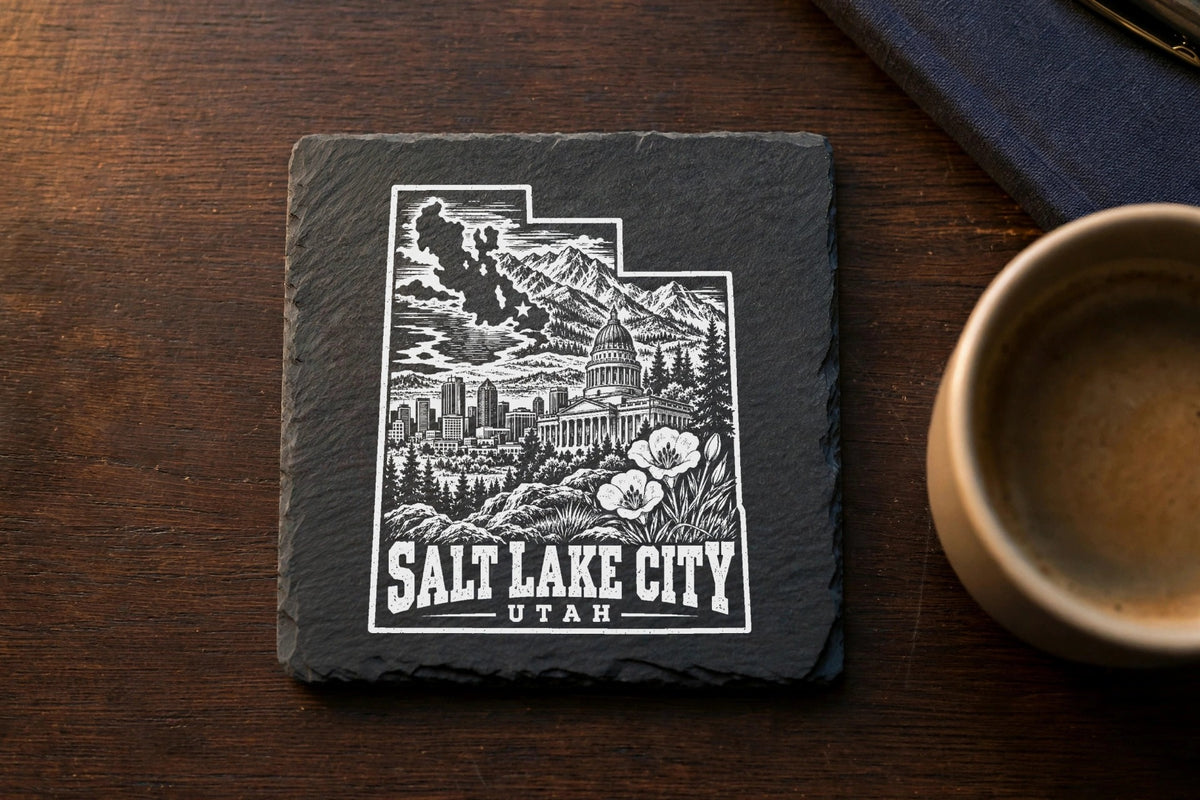 Square black slate coaster engraved with a Salt Lake City, Utah graphic design on a wooden table.