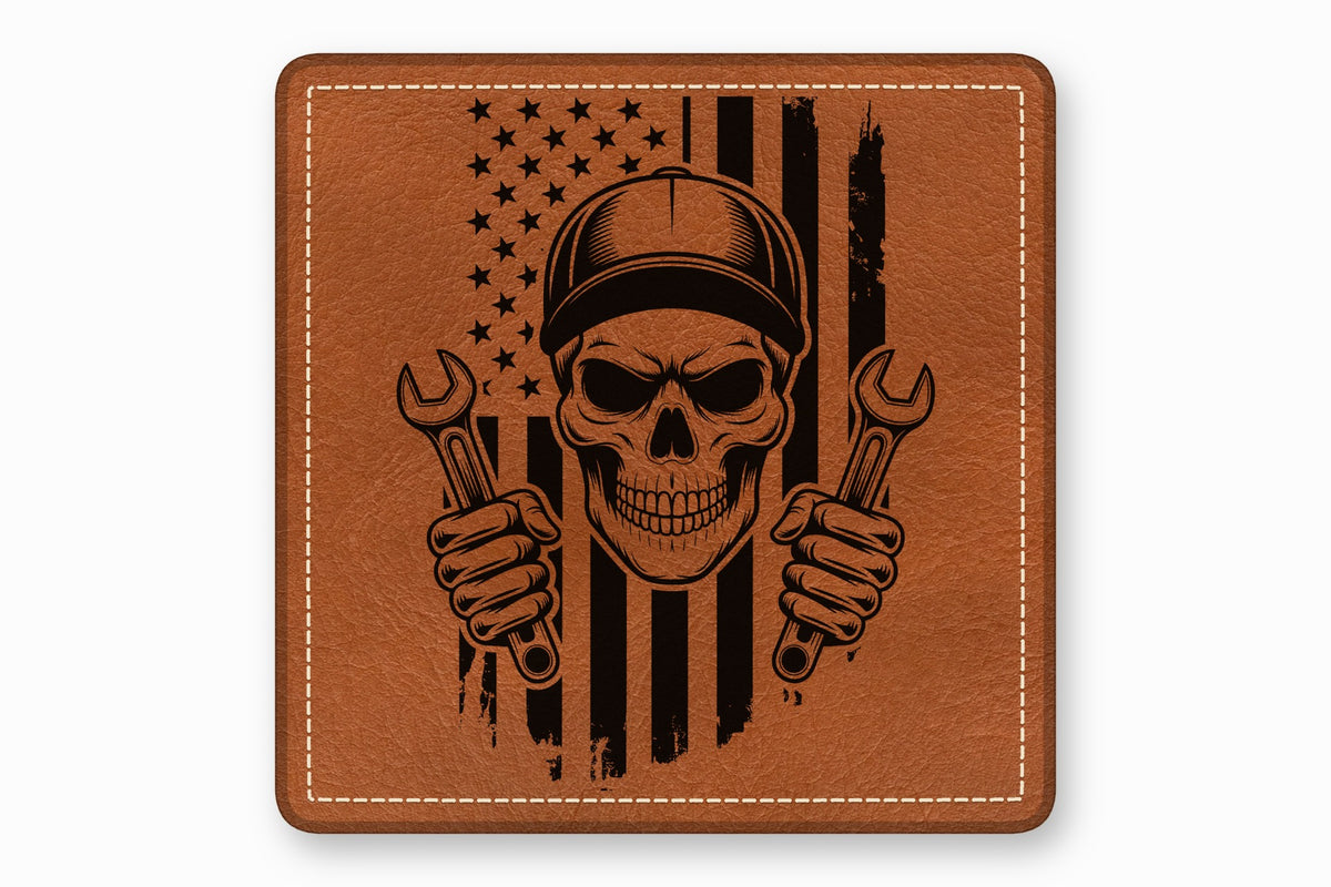 Brown leather patch with a stitched border and a black laser-engraved graphic of a skull holding wrenches over an American flag.