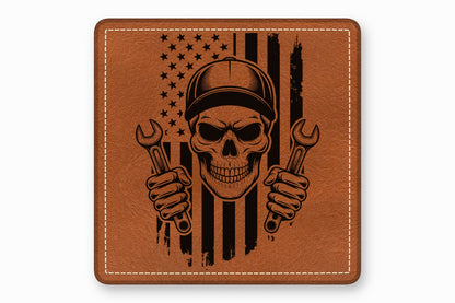 Brown leather patch with a stitched border and a black laser-engraved graphic of a skull holding wrenches over an American flag.