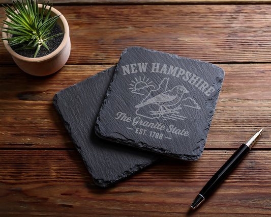 New Hampshire slate coasters engraved with a bird, sun, and "The Granite State - Est. 1788".