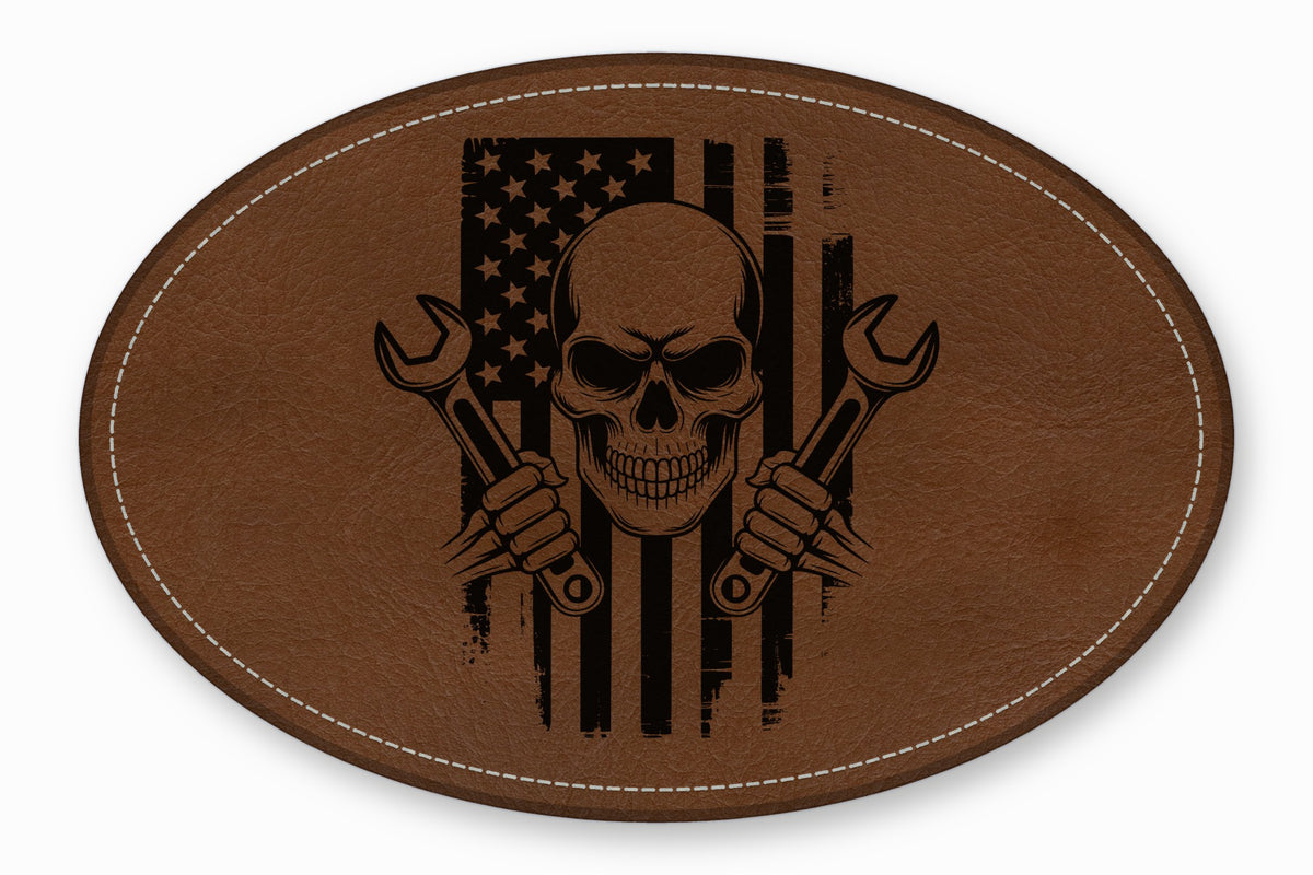 An oval brown leather patch with white stitching featuring a skull, crossed wrenches, and an American flag.