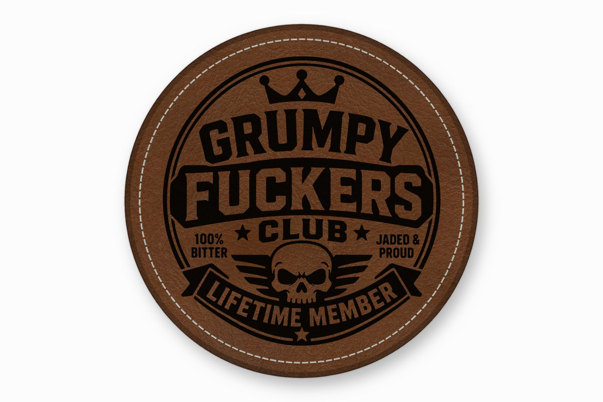 Round brown leather coaster featuring a stitched border and a black Grumpy Fuckers Club emblem.