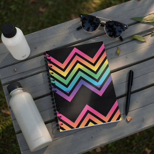 Spiral notebook with a black background and rainbow zigzag pattern.