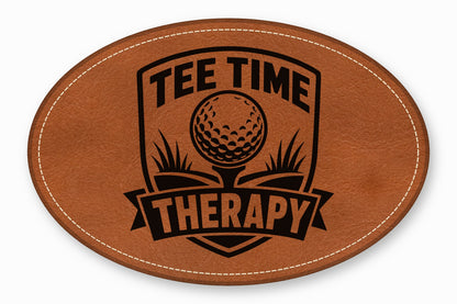 An oval brown leather patch with white stitching featuring a black golf emblem and text reading "TEE TIME THERAPY".