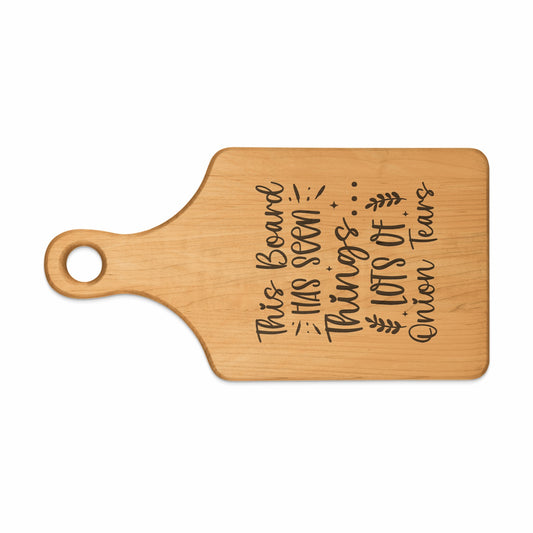 Wooden cutting board with engraved text: "This Board Has Seen Lots of Onion Tears."