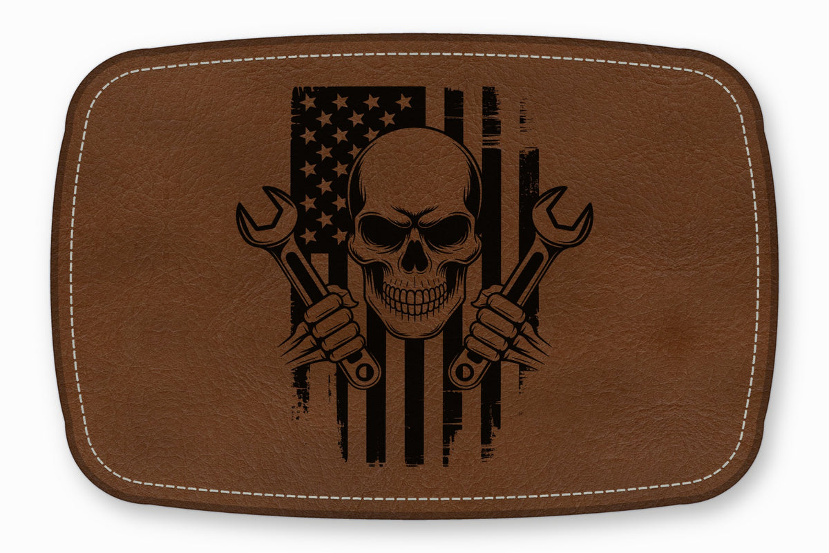 Brown leather patch featuring a black laser-engraved skull holding two wrenches over a distressed American flag.