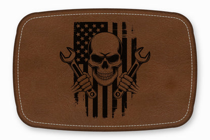 Brown leather patch featuring a black laser-engraved skull holding two wrenches over a distressed American flag.