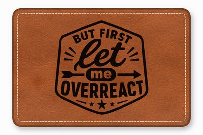 Brown leather patch with white stitched edges featuring the black text But First Let Me Overreact.