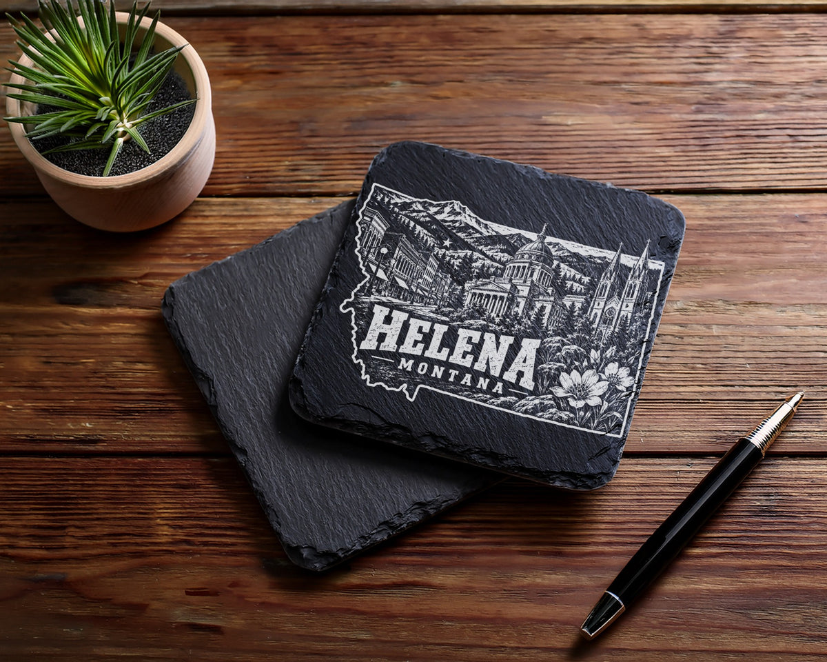 Two square black slate coasters featuring a white engraved Helena Montana skyline design on a wooden table.