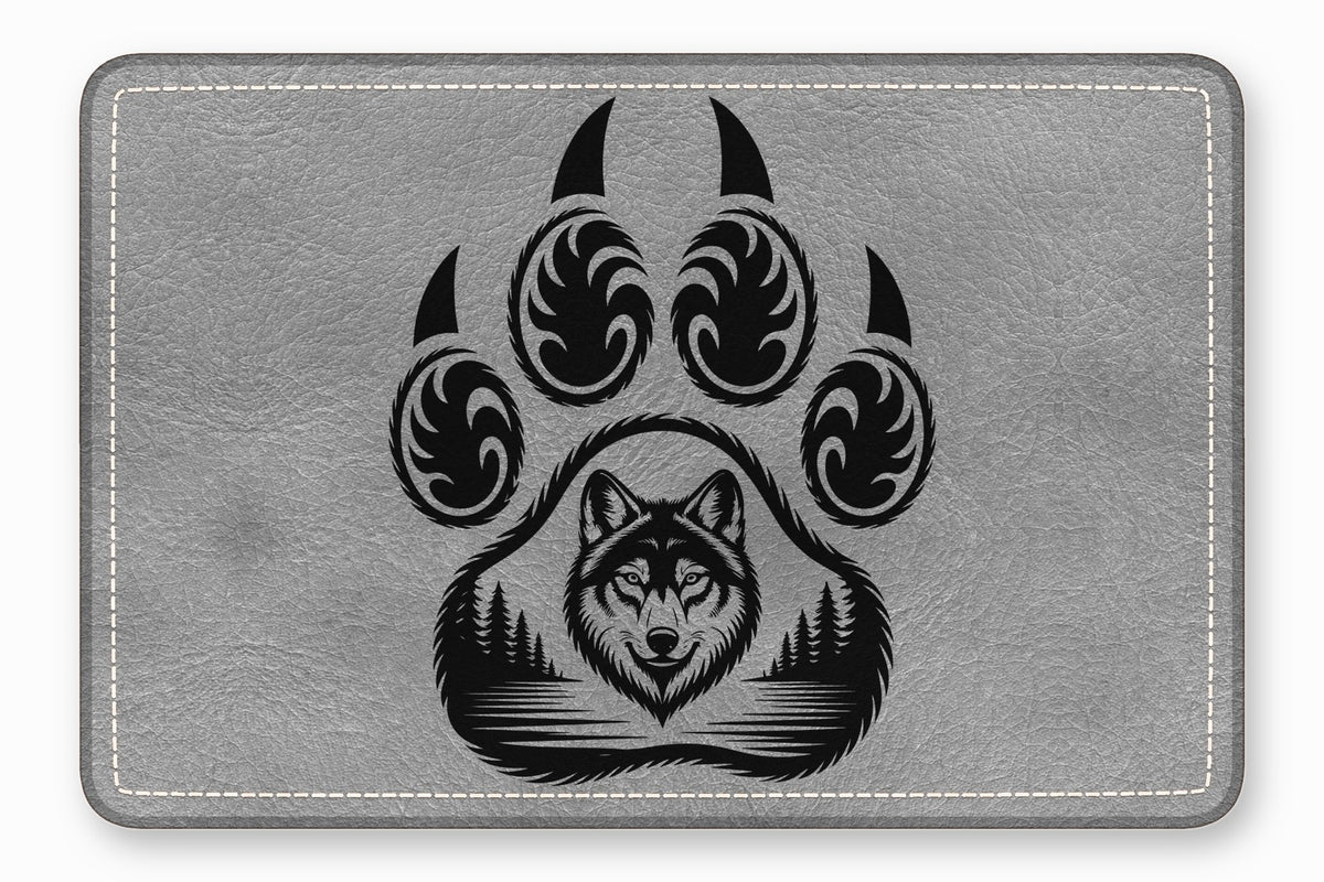 Grey rectangular leather patch with rounded corners featuring a black engraved paw print containing a wolf and forest design.