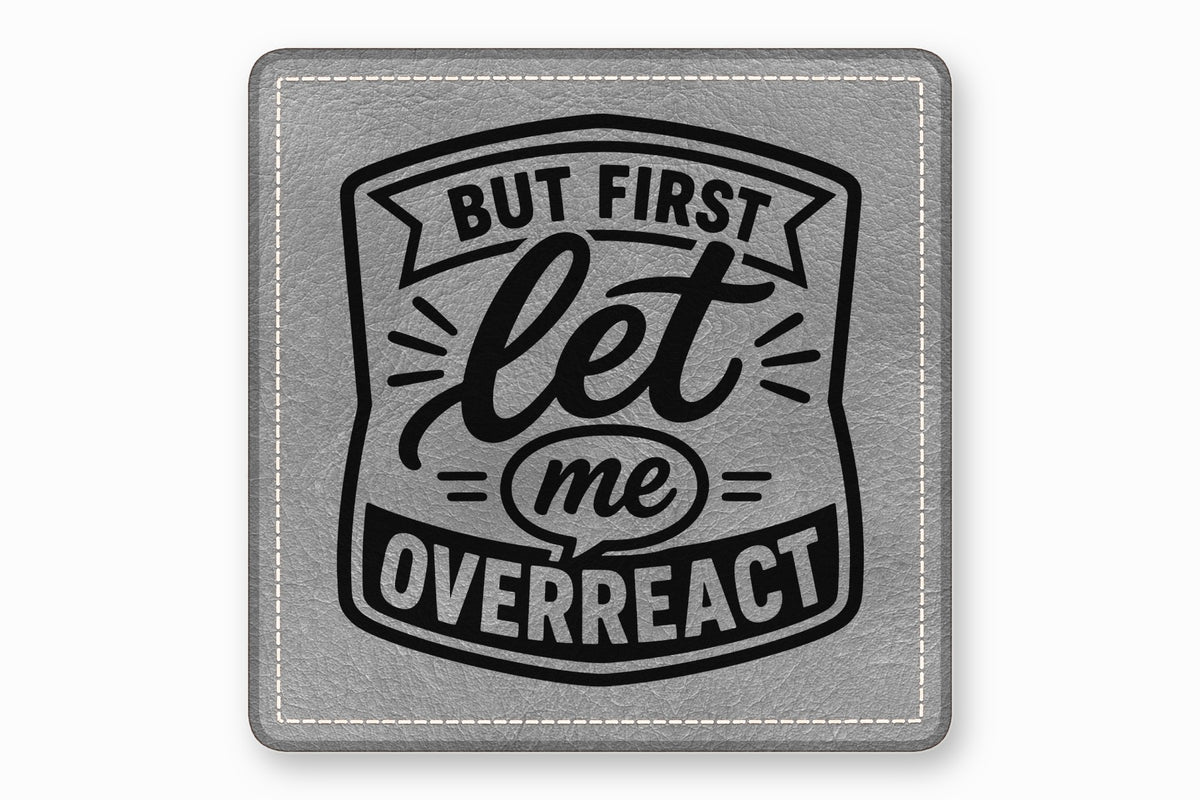 Square grey leather patch with white stitched border, featuring the black text But First Let Me Overreact.