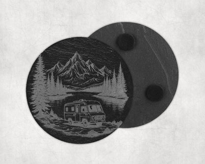 Circular coaster with engraved mountain, forest, and camper scene.