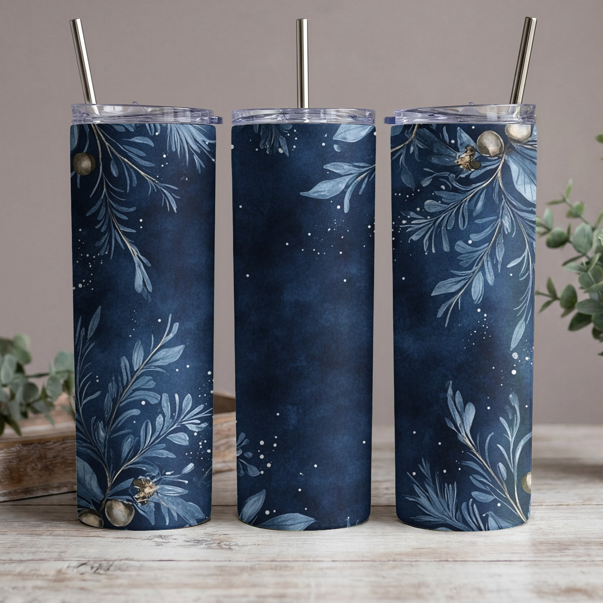Three tumblers with a dark blue floral and berry design and metal straws.