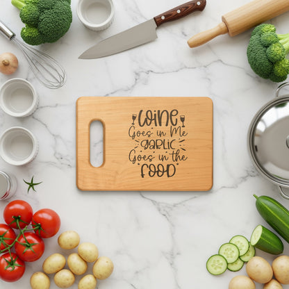 Wooden cutting board with "Wine Goes in Me Garlic Goes in the Food" text surrounded by fresh ingredients.
