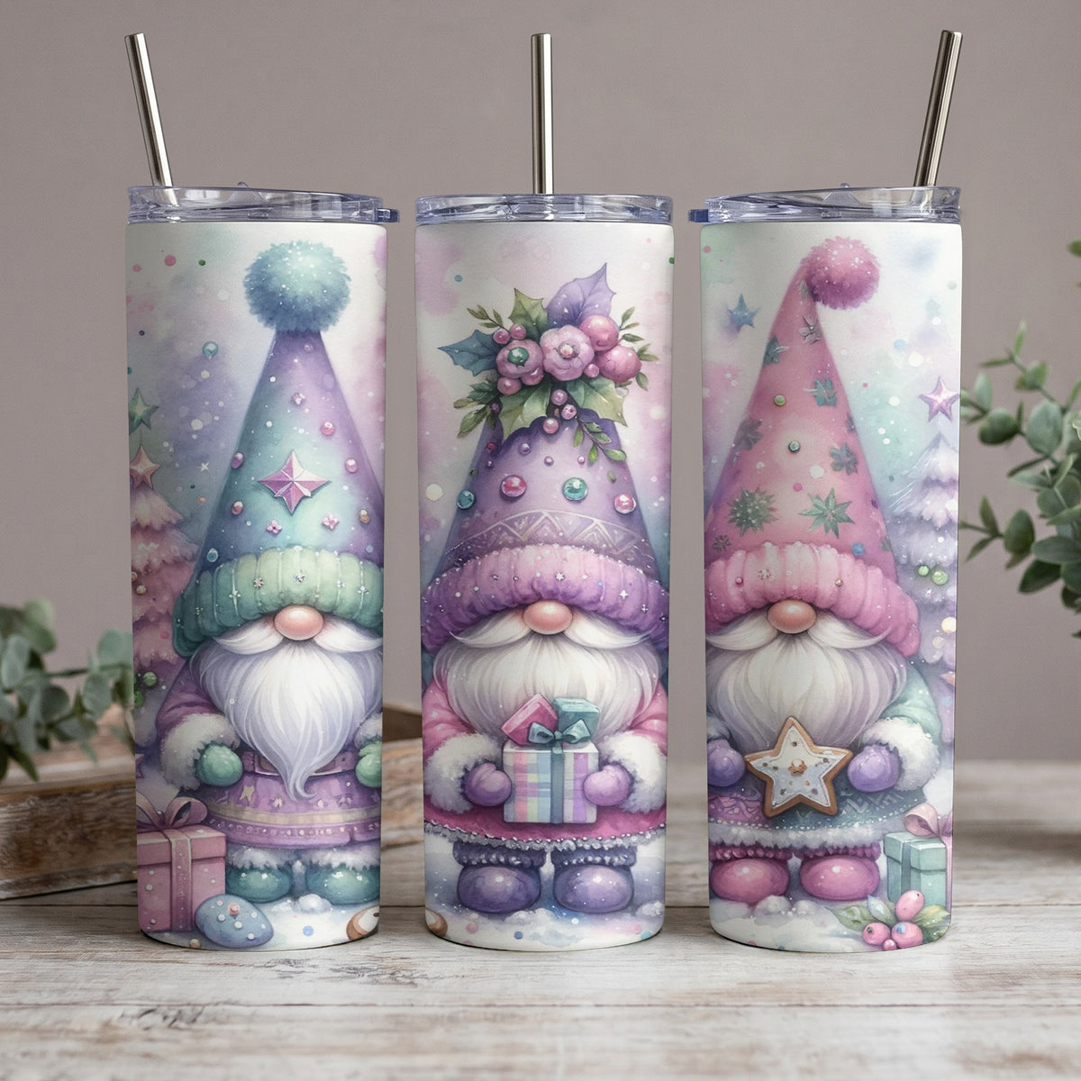 Three pastel tumblers featuring watercolor gnomes with gifts and wintery designs.