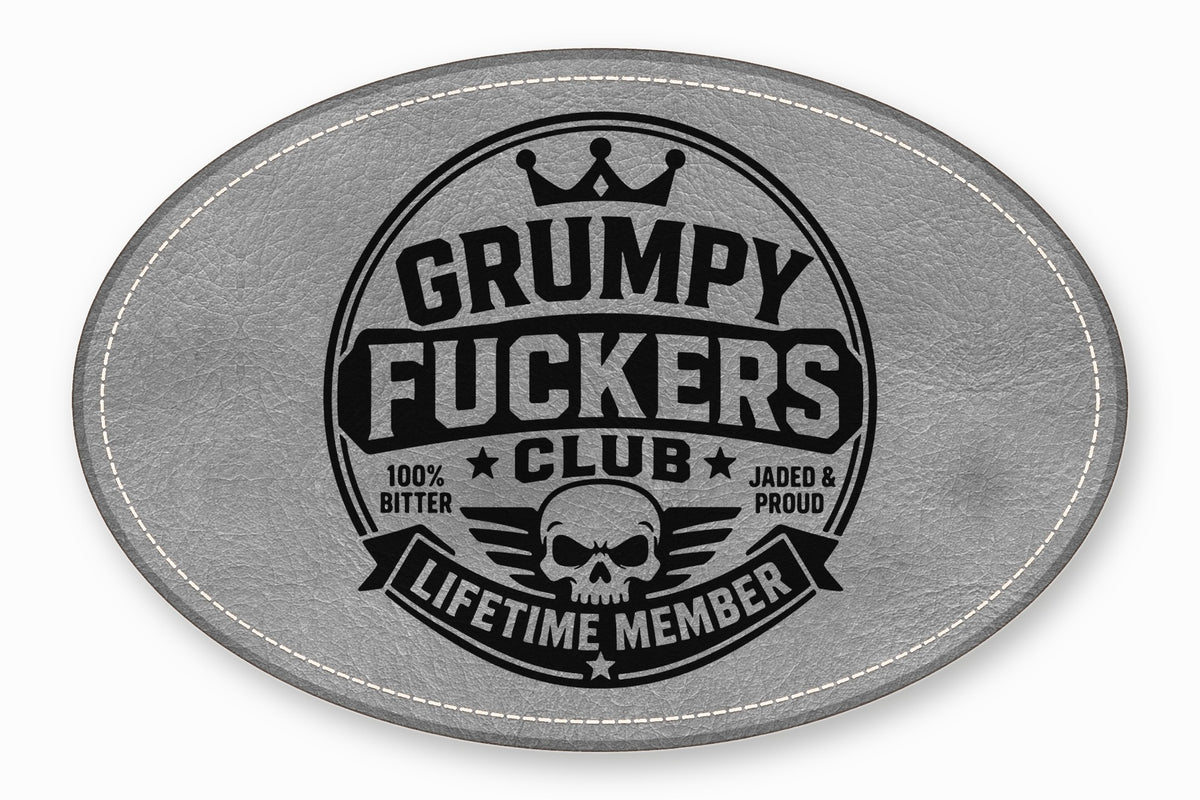 Oval grey leather patch with white stitched border featuring a black emblem with a skull, crown, and text.