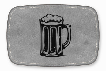 A grey leather placemat features a black engraved illustration of a frothy beer stein.