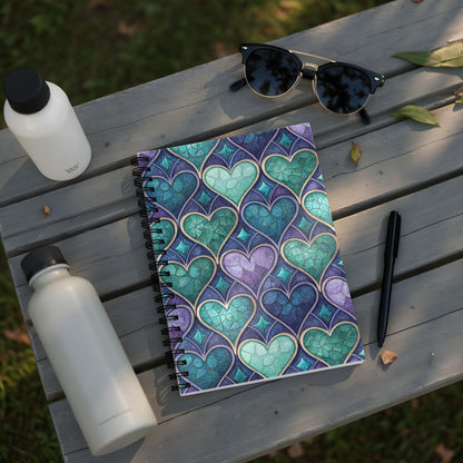 Notebook with stained glass heart pattern in purple and teal on a wooden table.
