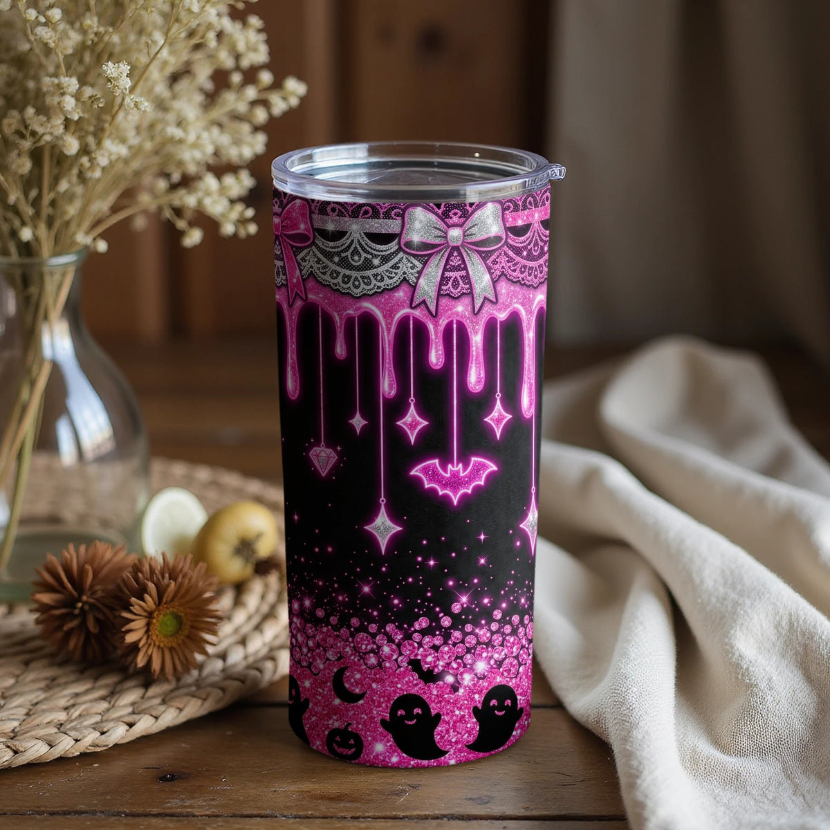 Pink glittery tumbler with Halloween ghosts, bats, moons, and diamonds on a black background.