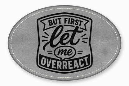 Gray oval leather patch with white stitched borders and black text reading But first let me overreact.