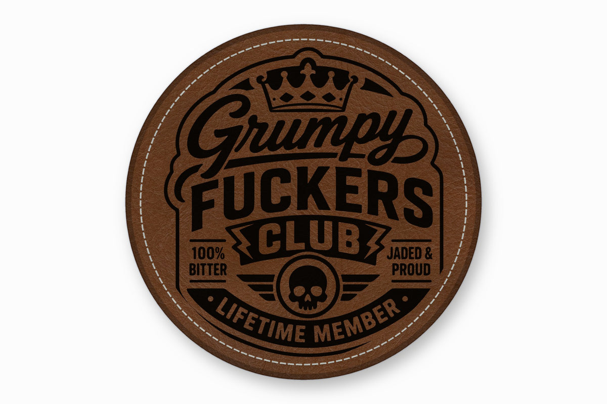 Round brown faux leather patch with white stitched border featuring debossed text Grumpy Fuckers Club and a skull emblem.