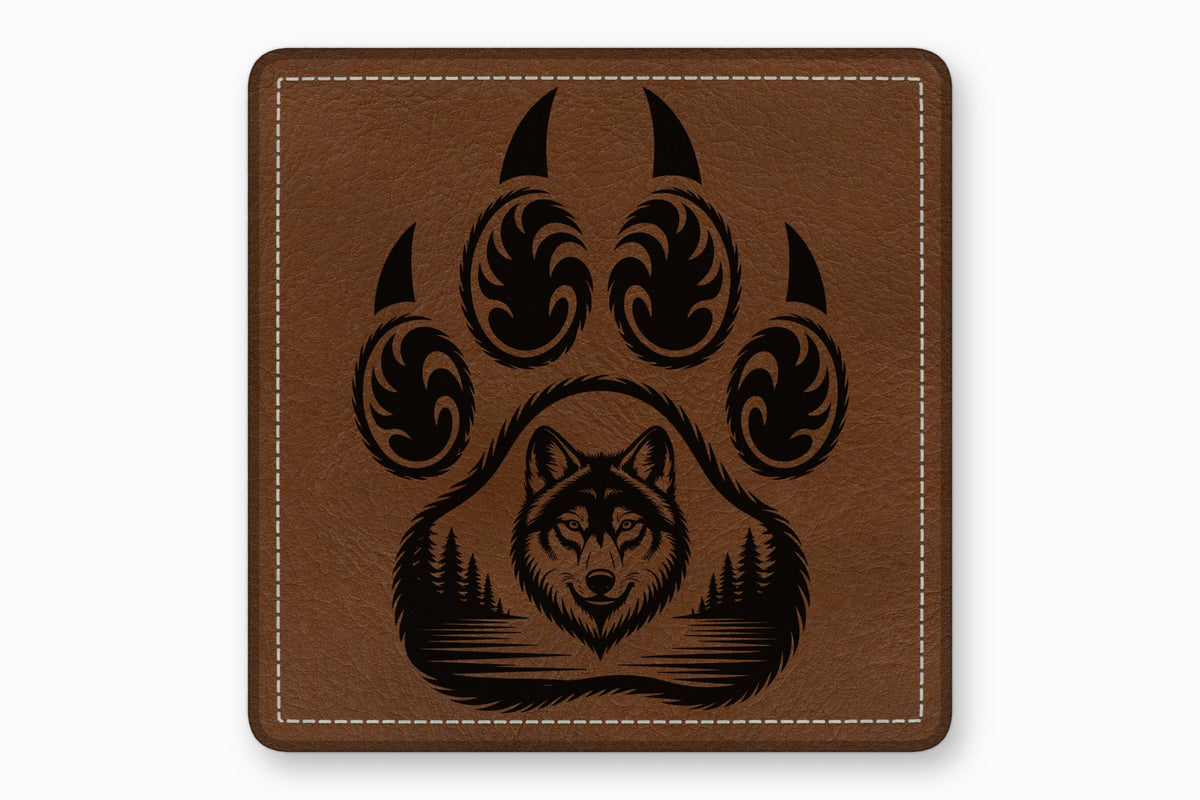 Brown leather square patch with white edge stitching and a black engraved wolf paw and forest design.